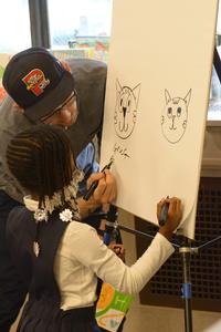 Artist Greg Pizzoli draws with a child at the Summer of Wonder Kickoff.